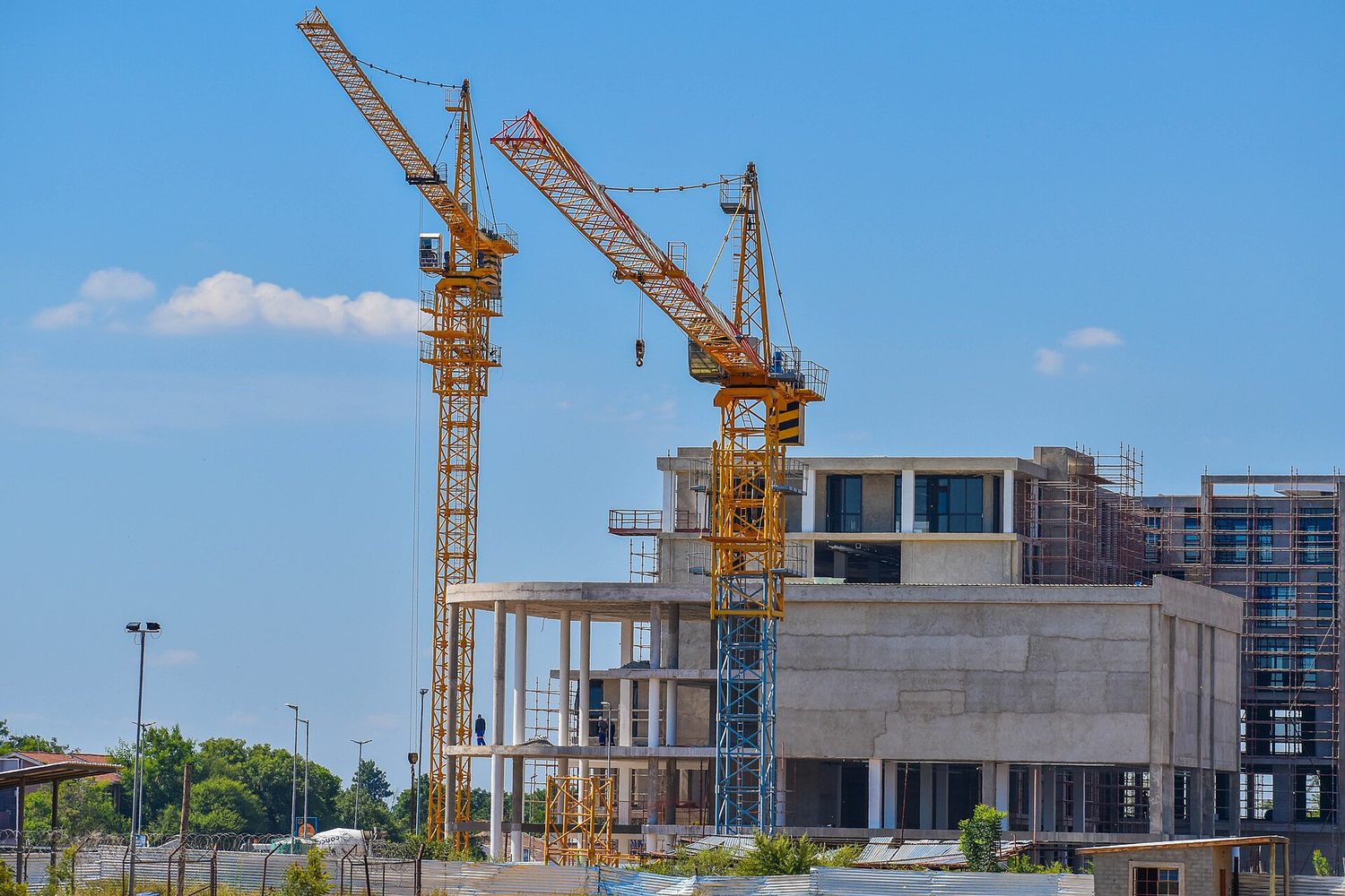 Tower cranes on a city building site, each with its long jib and a counterweight on the short arm behind the mast