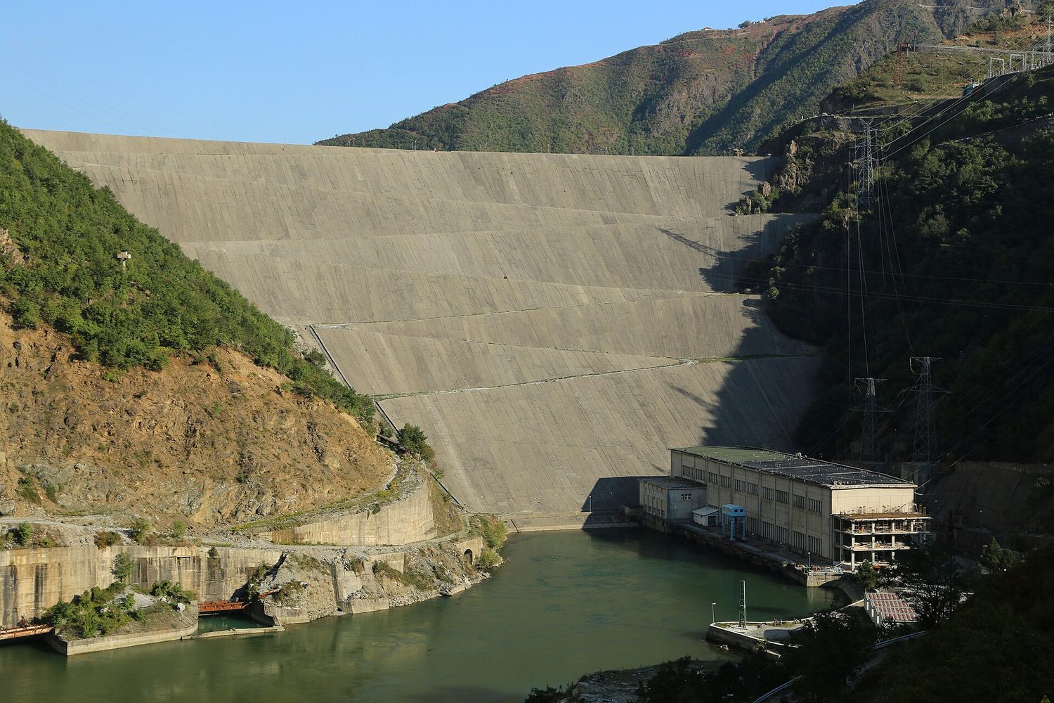A hydroelectric dam and power station, with water held high behind the wall