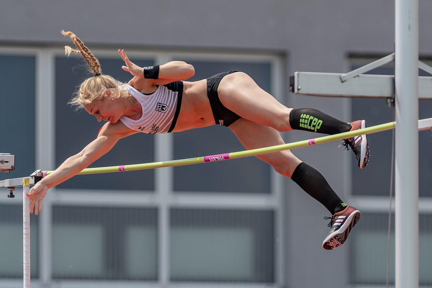 A pole vaulter at the moment of take-off, the pole bent almost double beneath them