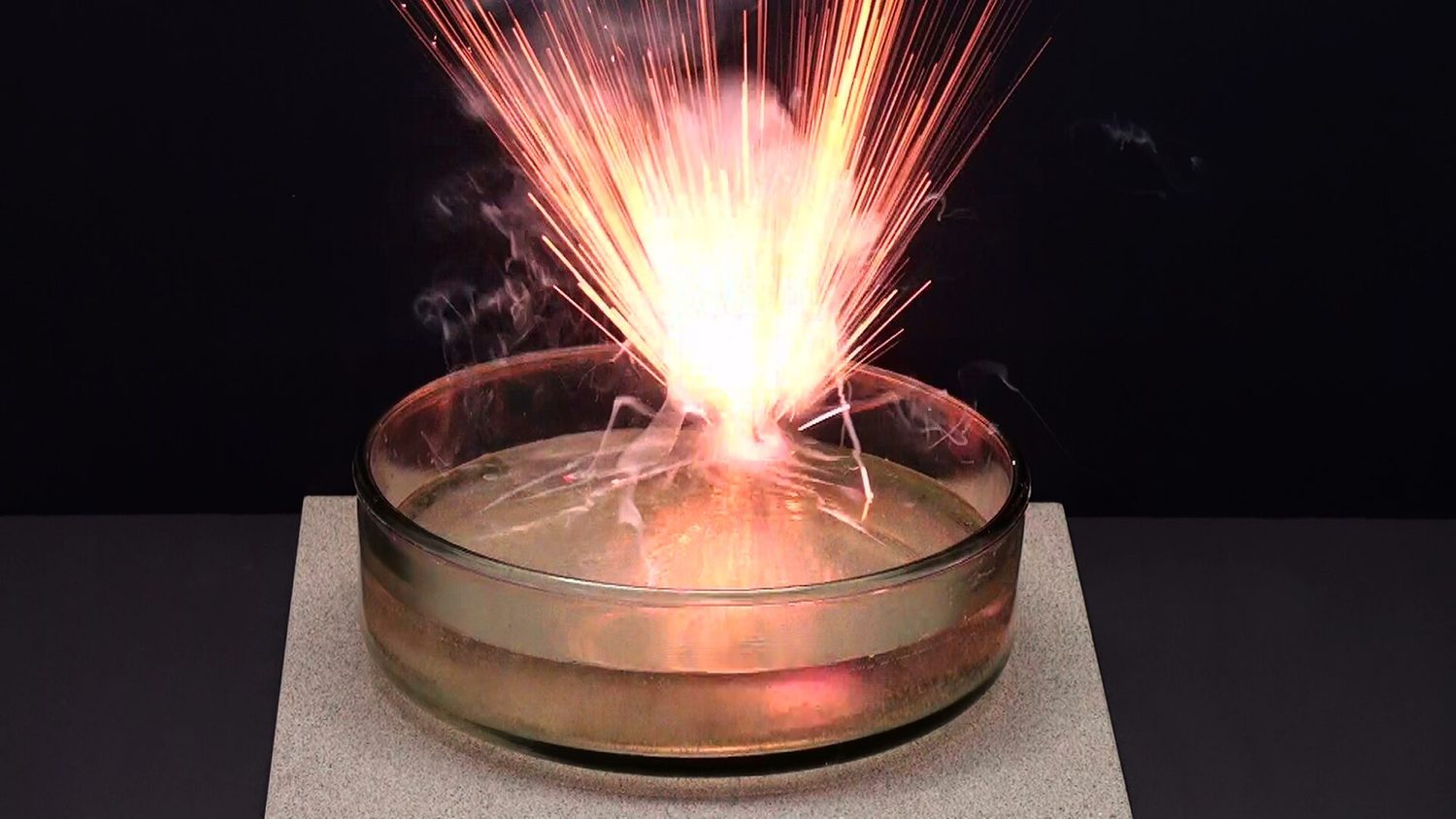 A small piece of potassium reacting violently on the surface of water with a lilac flame